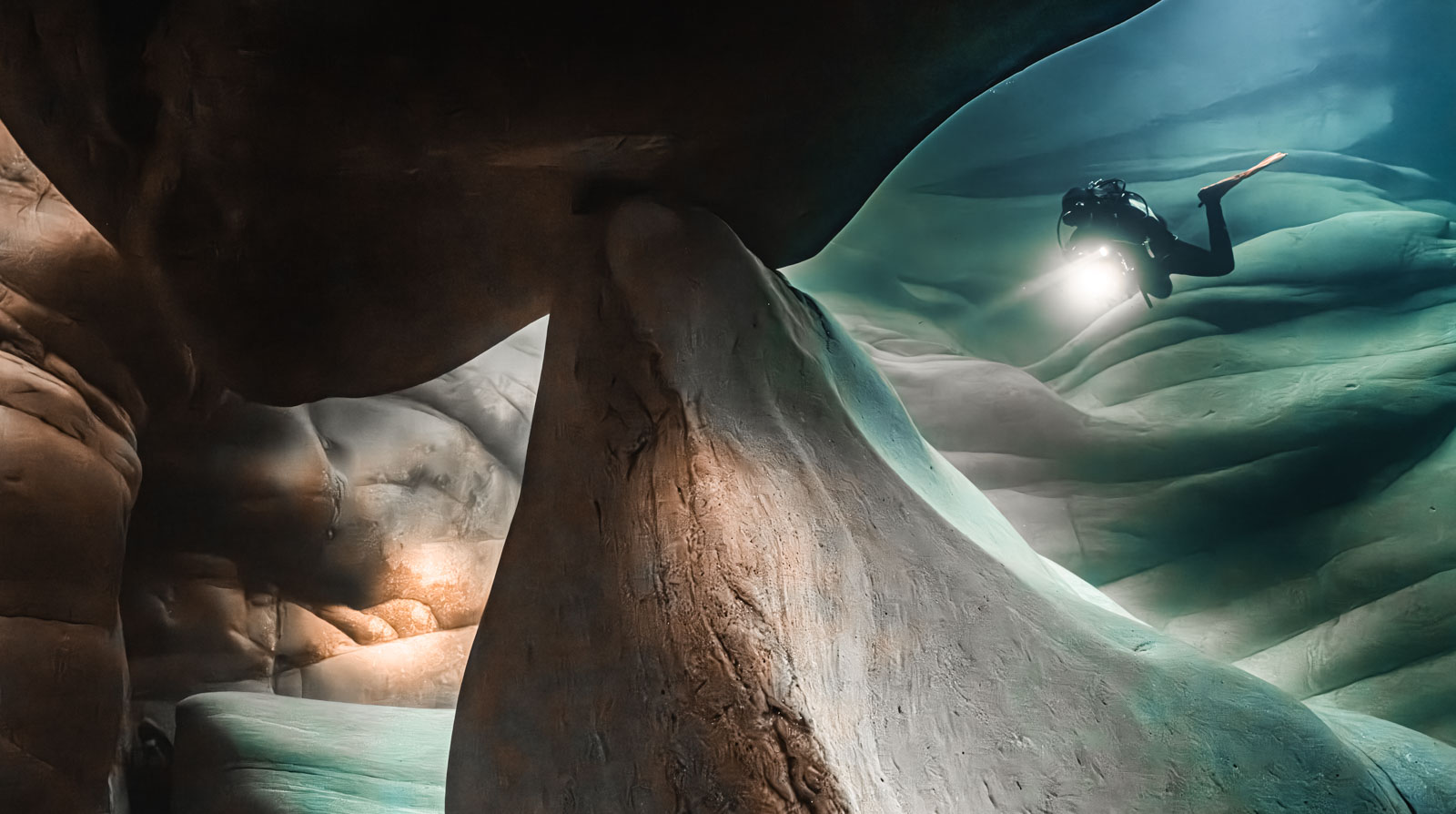 Diver among smoothly shaped rocks in clear water