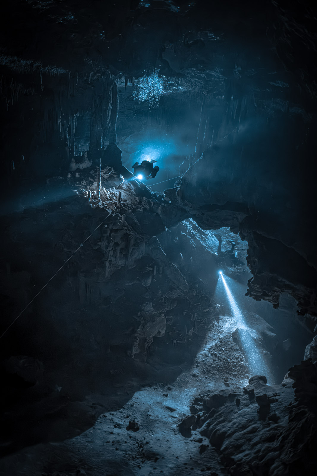 Zwei Taucher mit Lichtstrahlen auf unterschiedlichen Ebenen einer Unterwasserhöhle