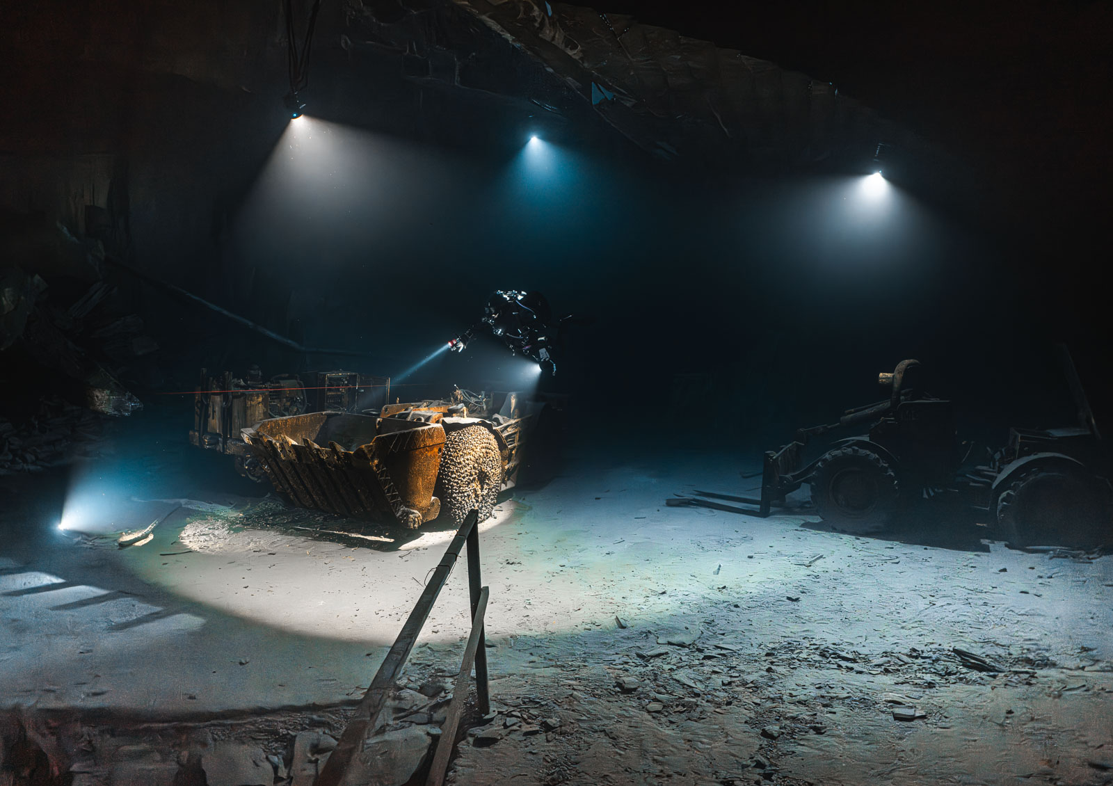Taucher neben einer alten Maschine unter mehreren Lichtstrahlen im Bergwerk